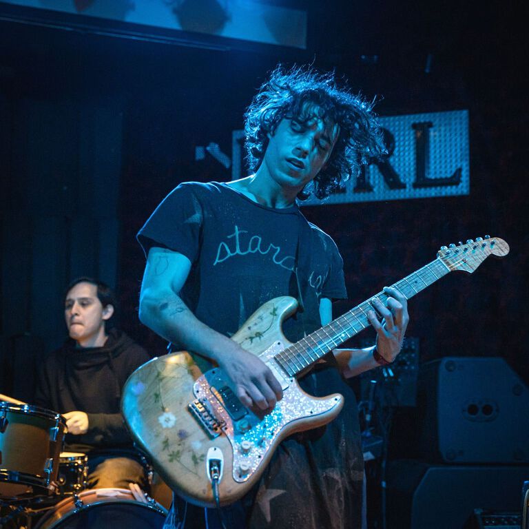Nick Llobet playing a guitar on stage